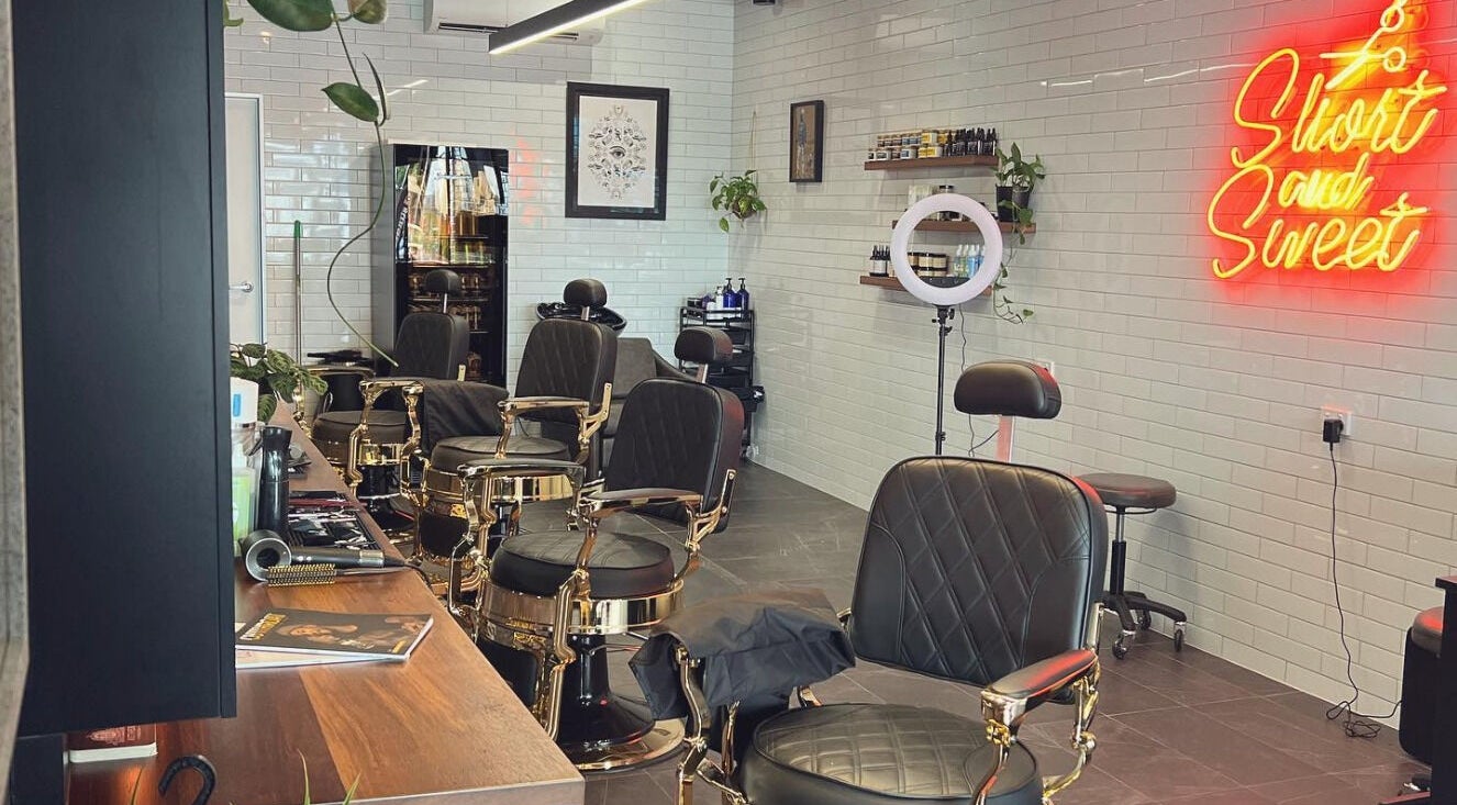 Interior of Short And Sweet Barbershop in Ashgrove, Queensland, AU featuring stylish barber chairs and neon sign.