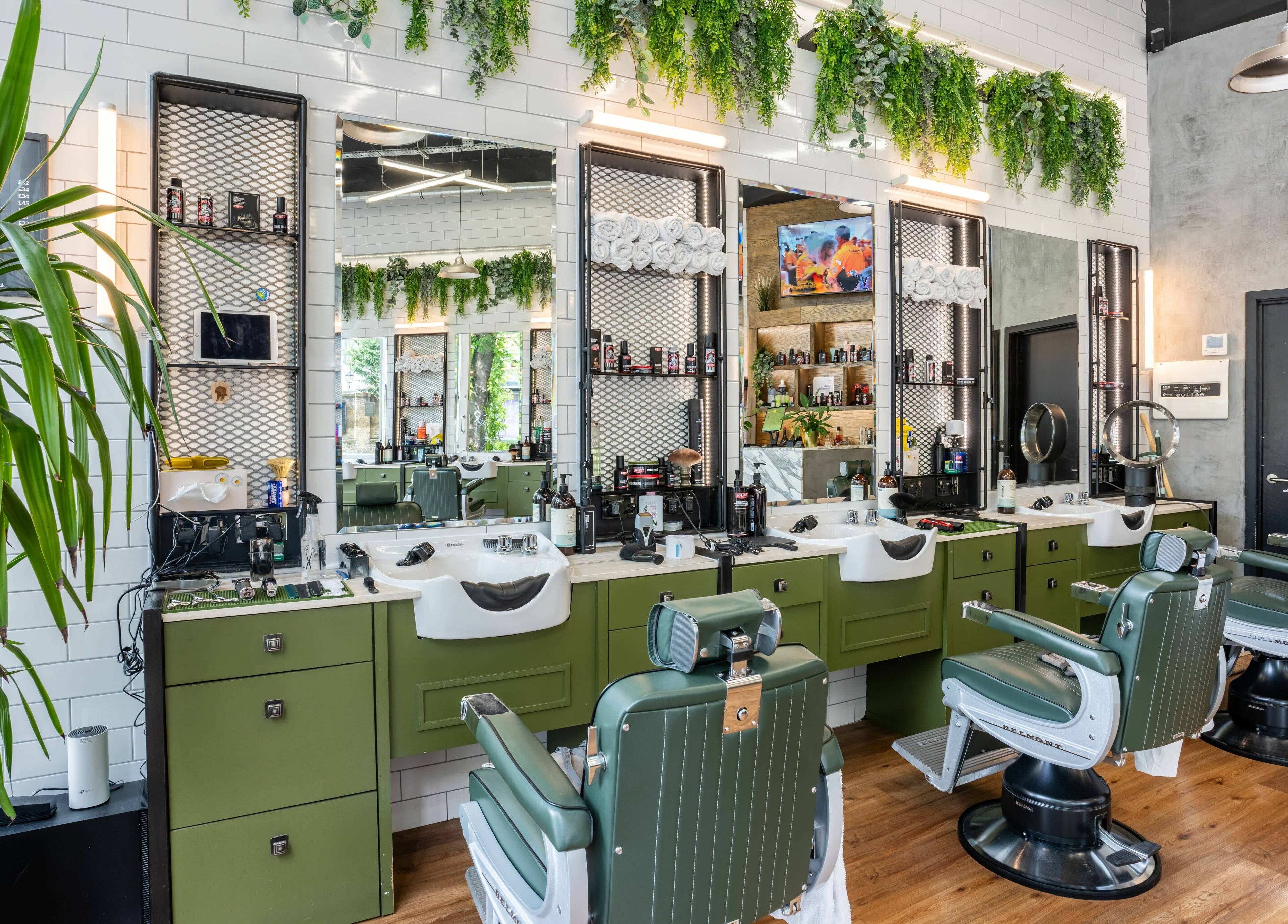 Elegant barbershop at The Axe Club in Camden, London, England, GB with vintage chairs and lush greenery.