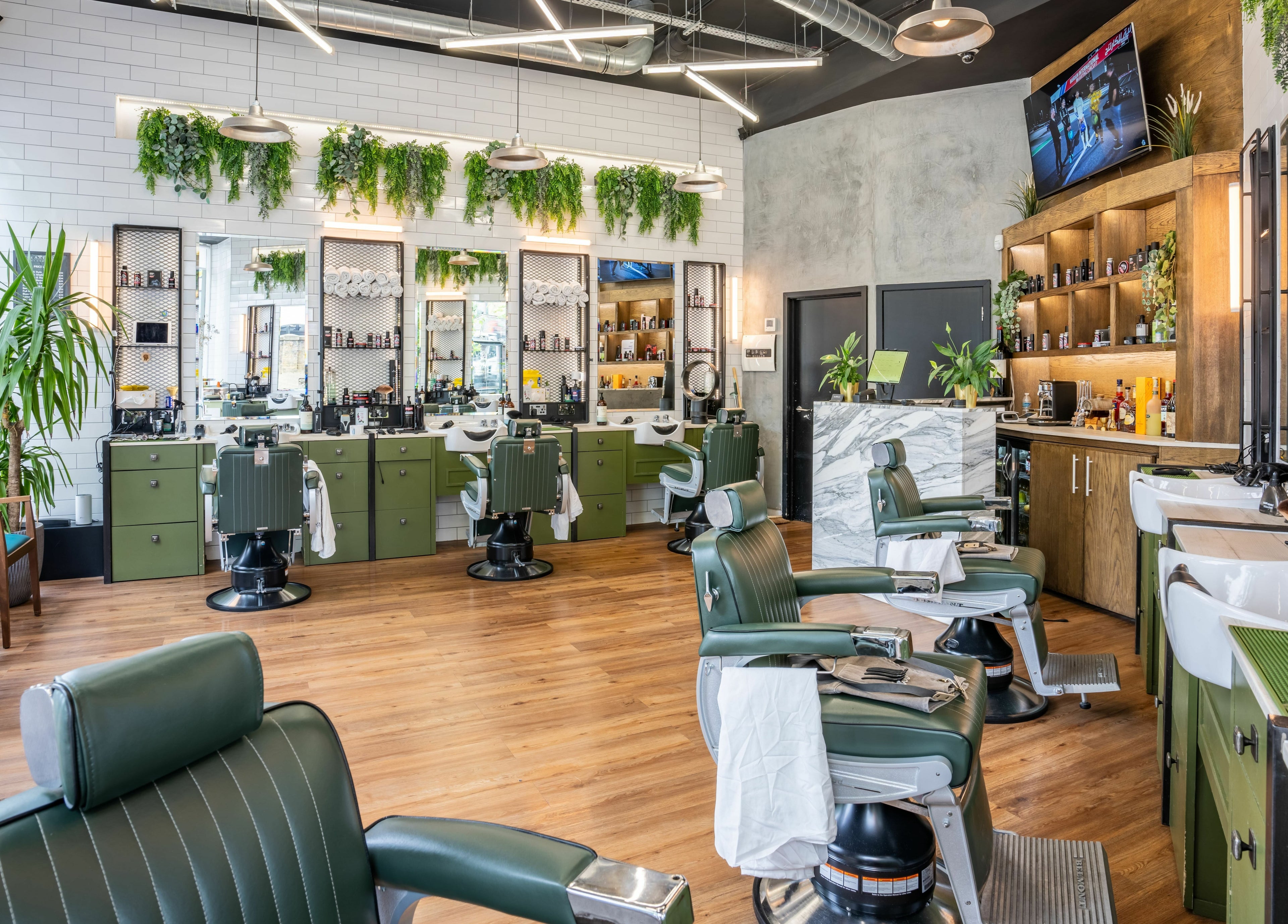 Elegant barbershop interior at The Axe Club in Camden, London, England, GB with green chairs and modern decor.