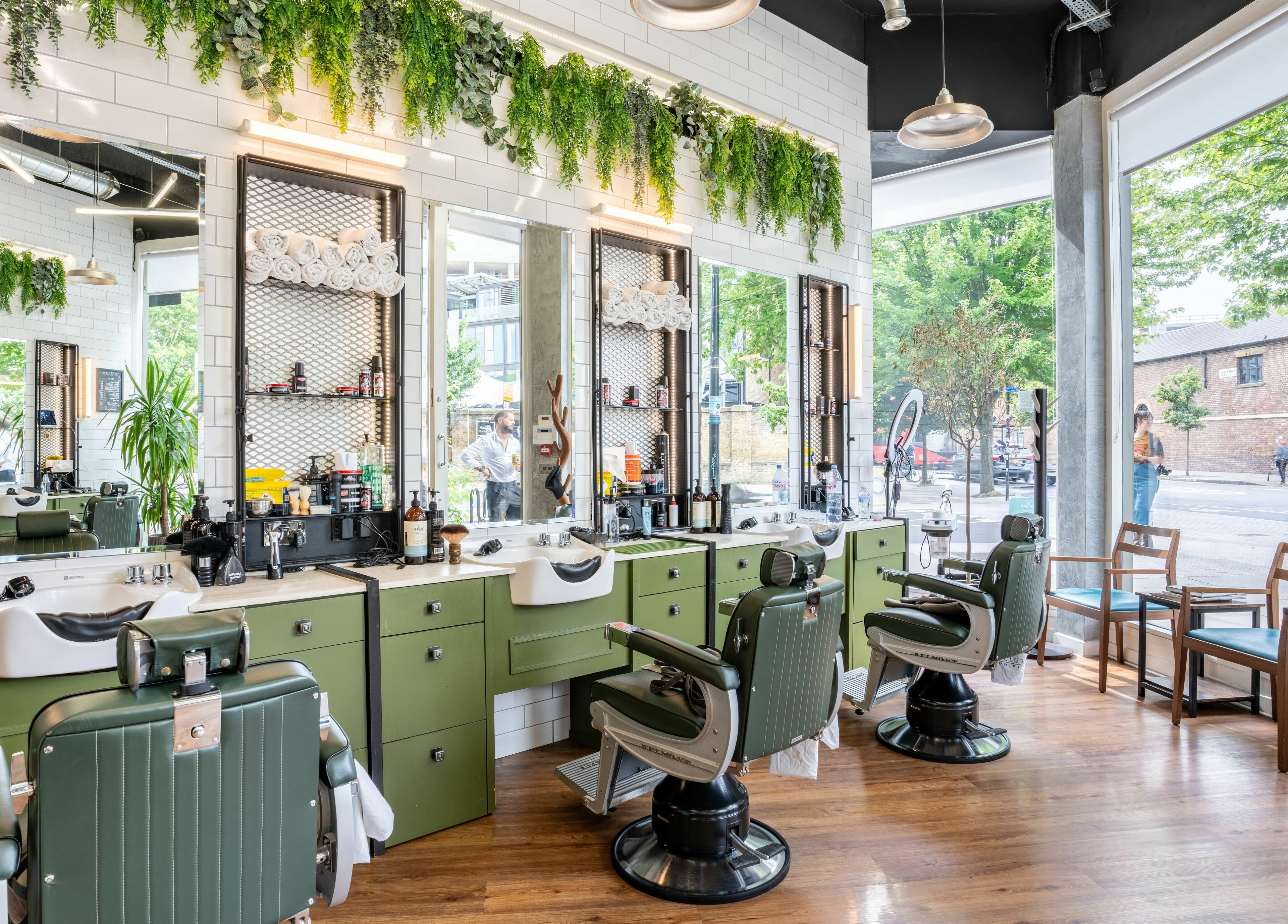 Stylish interior of The Axe Club in Camden, London, England, GB featuring green salon chairs and large, bright windows.
