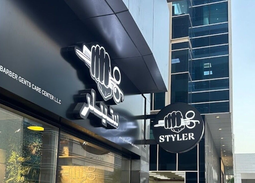 Entrance of Styler Gents Salon & Spa - Khalifa Park in Abu Dhabi, AE with bold signage and flags.