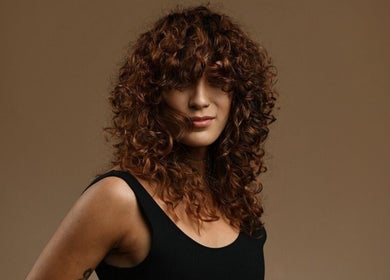 Elegant woman with curly hair at Excentric, Cape Town, Western Cape, ZA, showcasing trendy hairstyle.