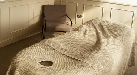 Calming massage room at Beauty Boutique, Denby Dale, England, GB with a cozy chair and massage table.
