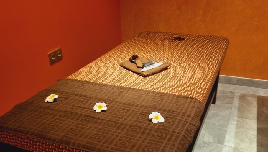 Massage table at Sanje Wellness Gading Serpong in Banten, Banten, ID, adorned with soft linens and flowers.
