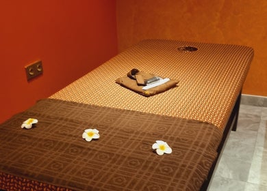 Massage table at Sanje Wellness Gading Serpong in Banten, Banten, ID, adorned with soft linens and flowers.