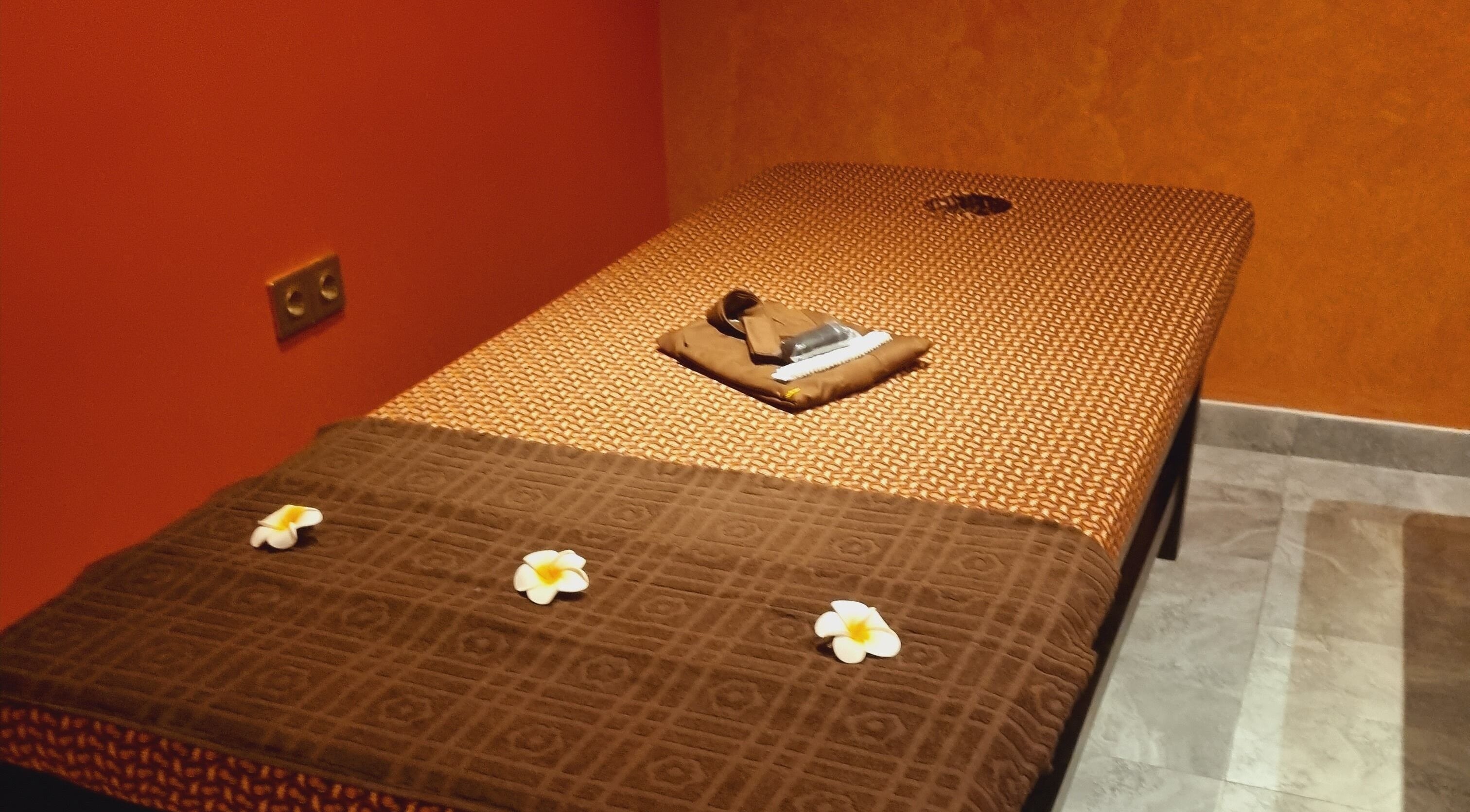Massage table at Sanje Wellness Gading Serpong in Banten, Banten, ID, adorned with soft linens and flowers.