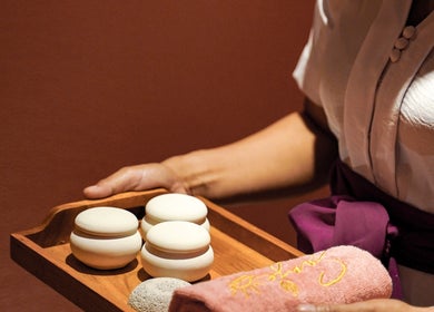 A spa therapist presenting a tray with relaxation stones and towel at Sanje Wellness Gading Serpong, Banten, Banten, ID.
