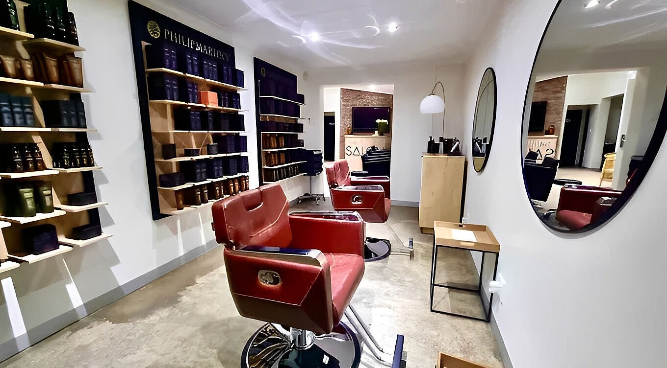 The Barber's stylish interior in Bloemfontein, Free State, ZA with red chairs and product displays.