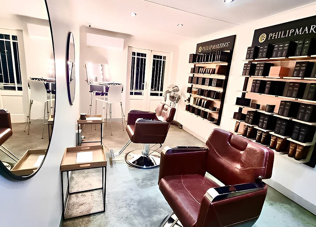 Modern salon interior of The Barber in Bloemfontein, Free State, ZA, featuring stylish leather chairs and lit mirrors.