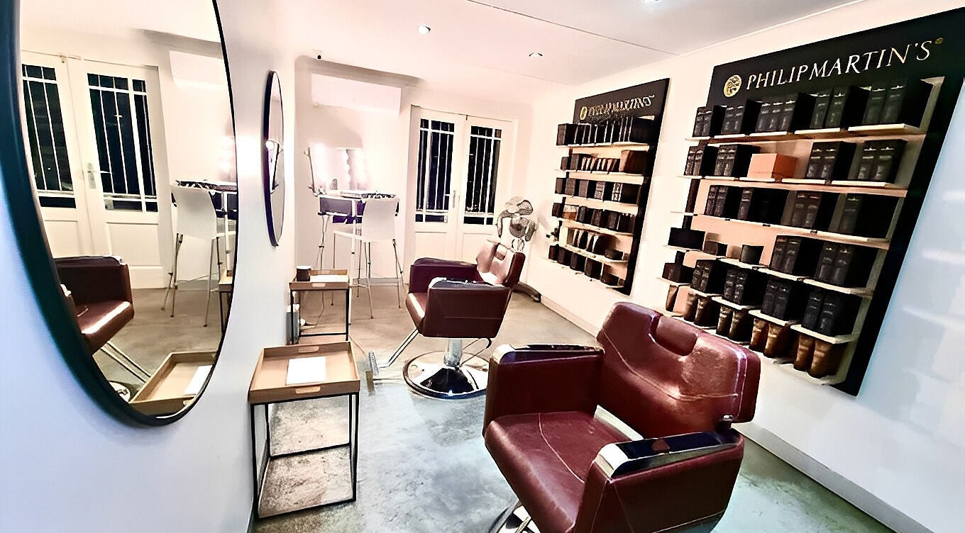 Modern salon interior of The Barber in Bloemfontein, Free State, ZA, featuring stylish leather chairs and lit mirrors.