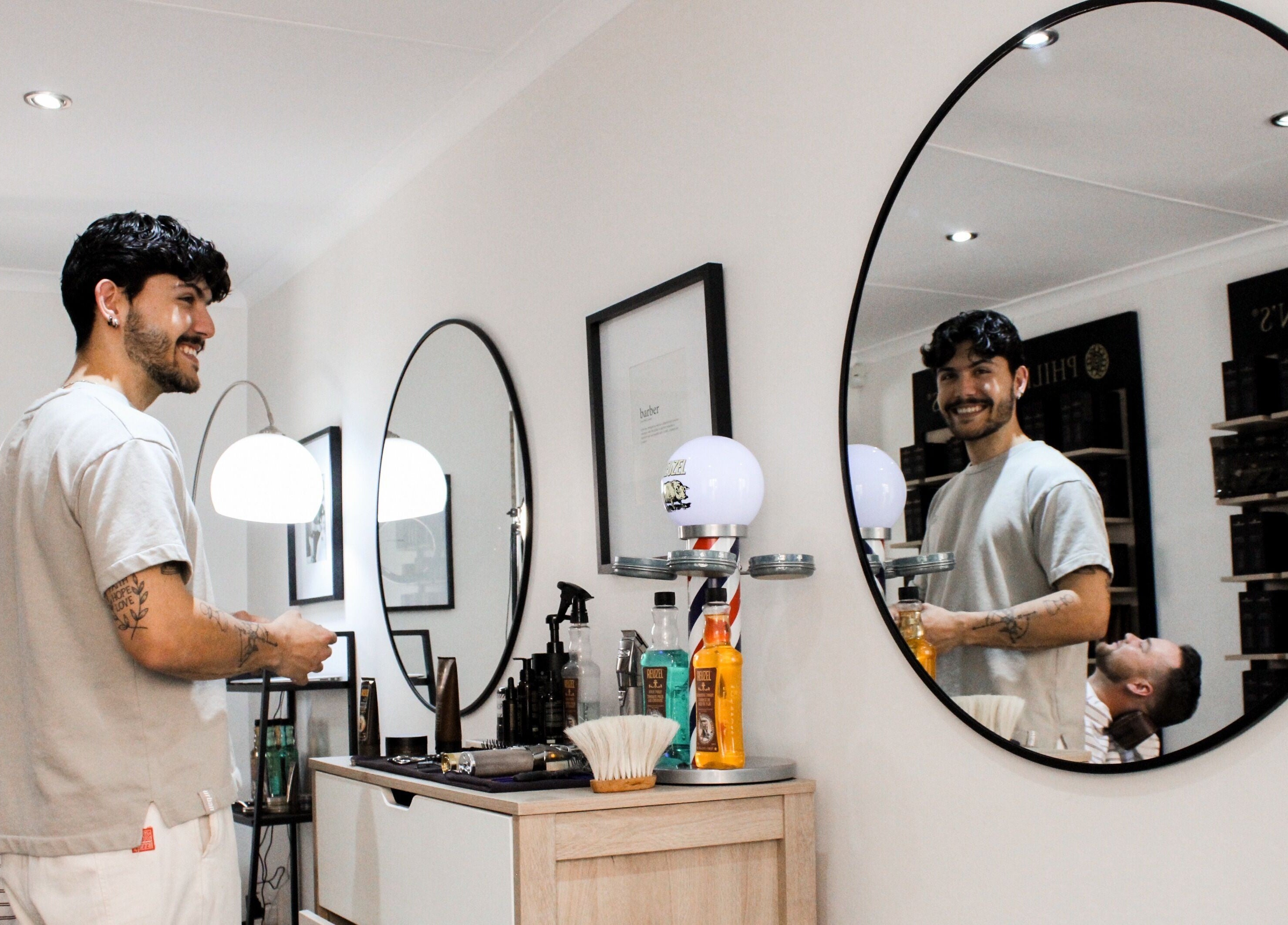 Barber smiling at The Barber in Bloemfontein, Free State, ZA, with a mirror reflection.