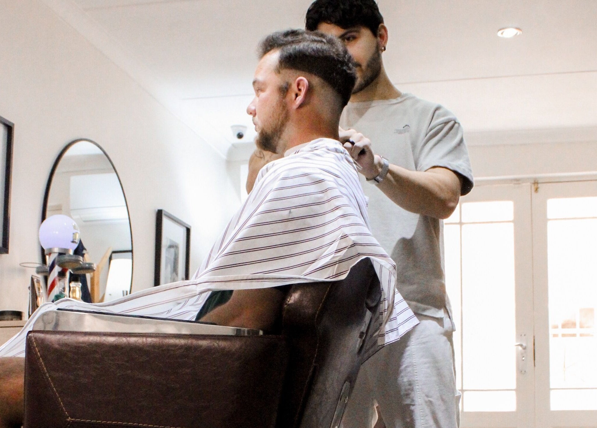 Client getting a stylish haircut at The Barber, Bloemfontein, Free State, ZA. Elegant, modern salon atmosphere.