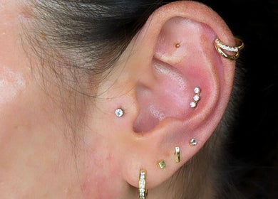 Ear piercings at Time Out Beauty, Piercing & Aesthetics in Chiddingfold, England, GB. Multiple earrings displayed.