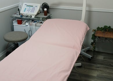 Comfortable treatment room at Unicorn Electrolysis, Columbus, Ohio, US, with pink-covered bed and equipment.