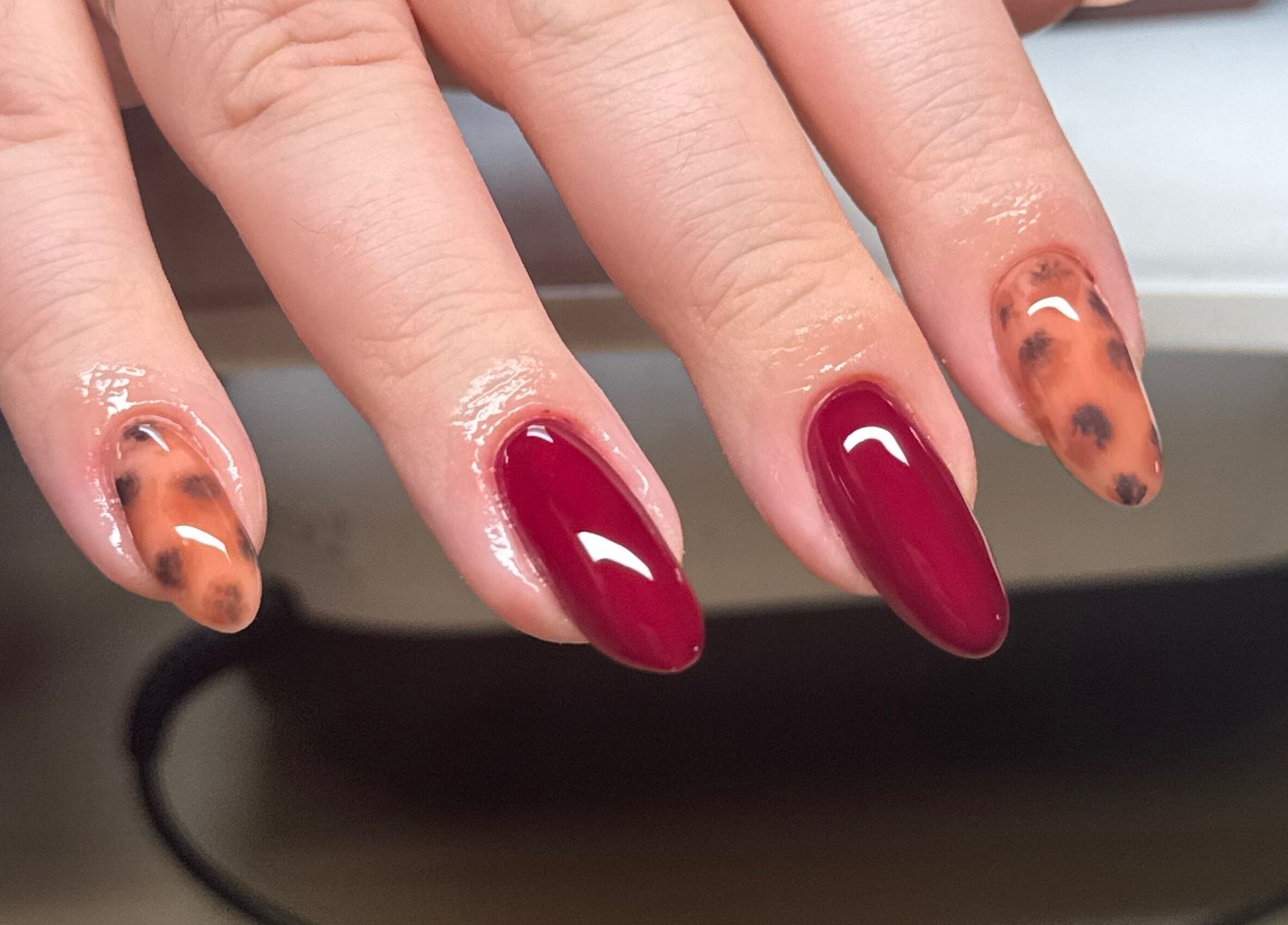 Stylish nail art with red and tortoiseshell design at Brahmaloka, High Wycombe, England, GB.