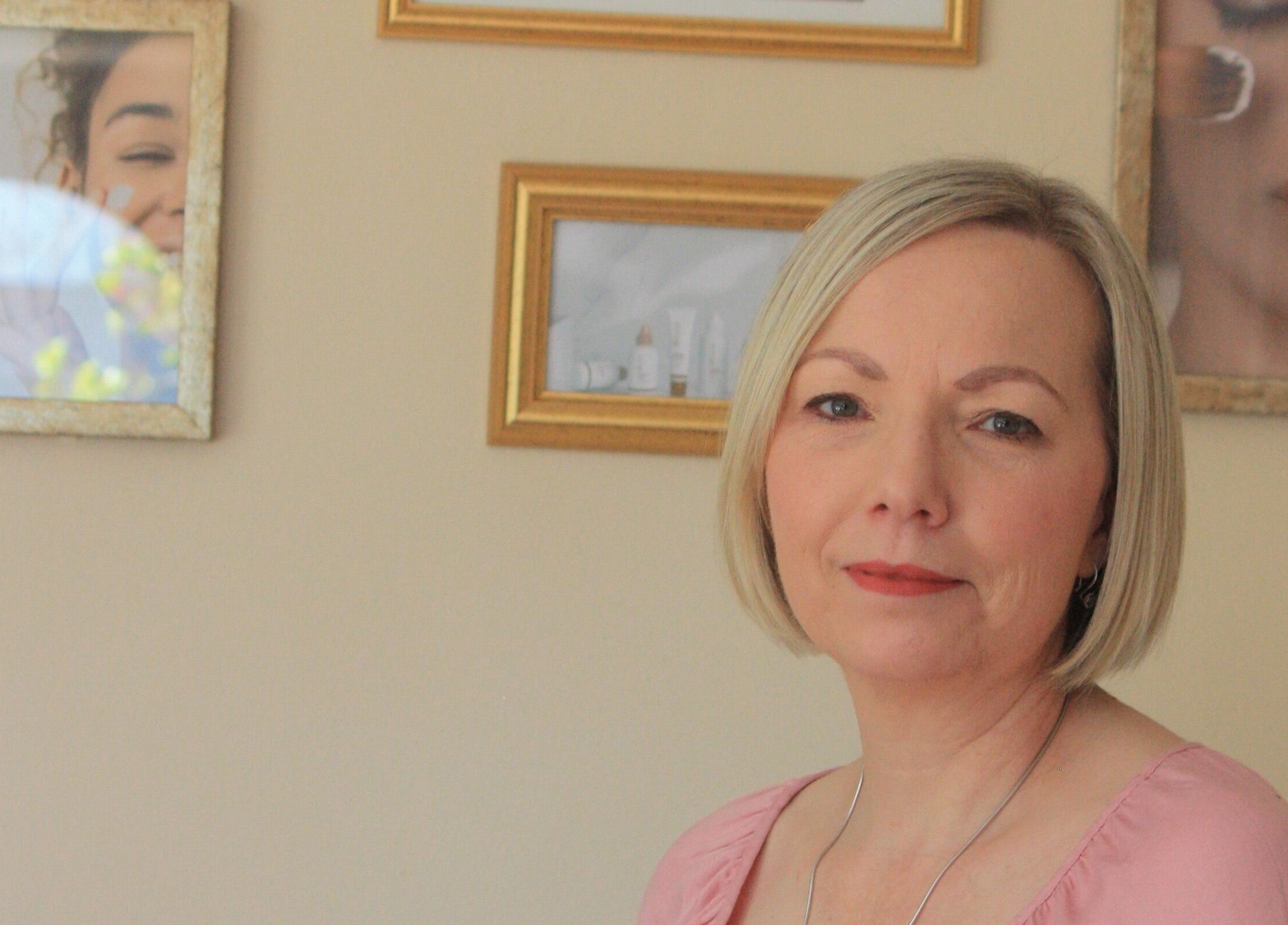 Woman in a pink top at Be You Holistic Wellness, Cape Town, Western Cape with serene framed art.