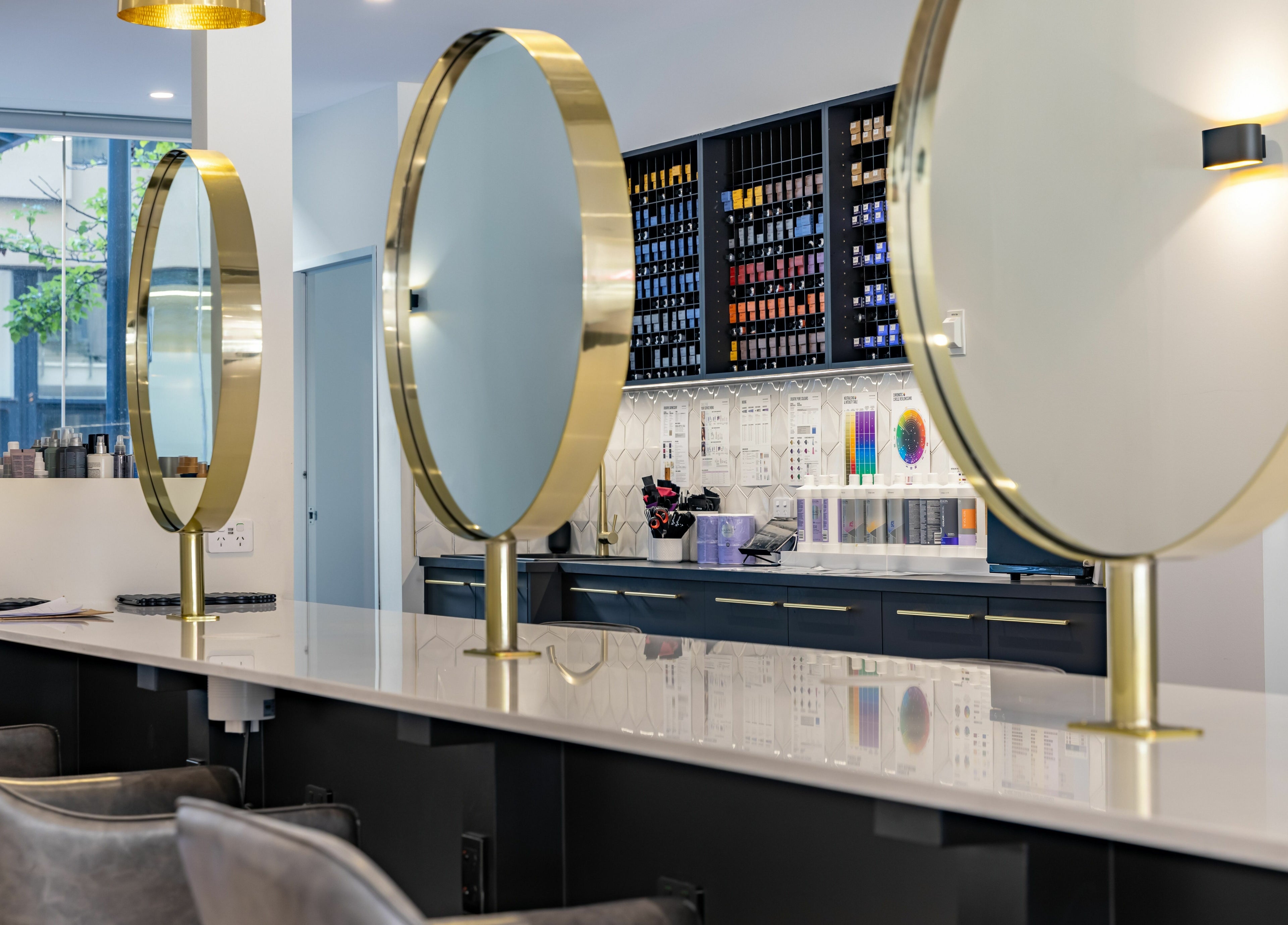 Elegant salon interior at Mooi Hair CBR, Canberra, with modern mirrors and beauty products displayed.