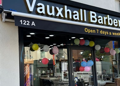 Vauxhall Barbers storefront with balloons in London, England, GB. Open 7 days a week. Welcoming exterior view.