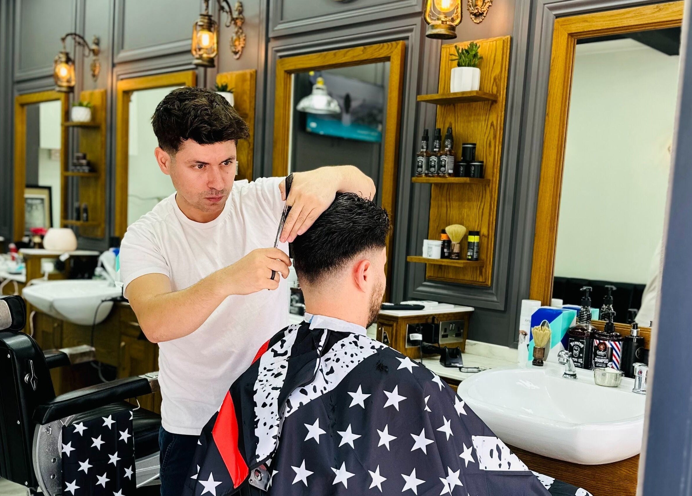 Professional barber at Vauxhall Barbers, London, England, GB giving precise haircut to a client.