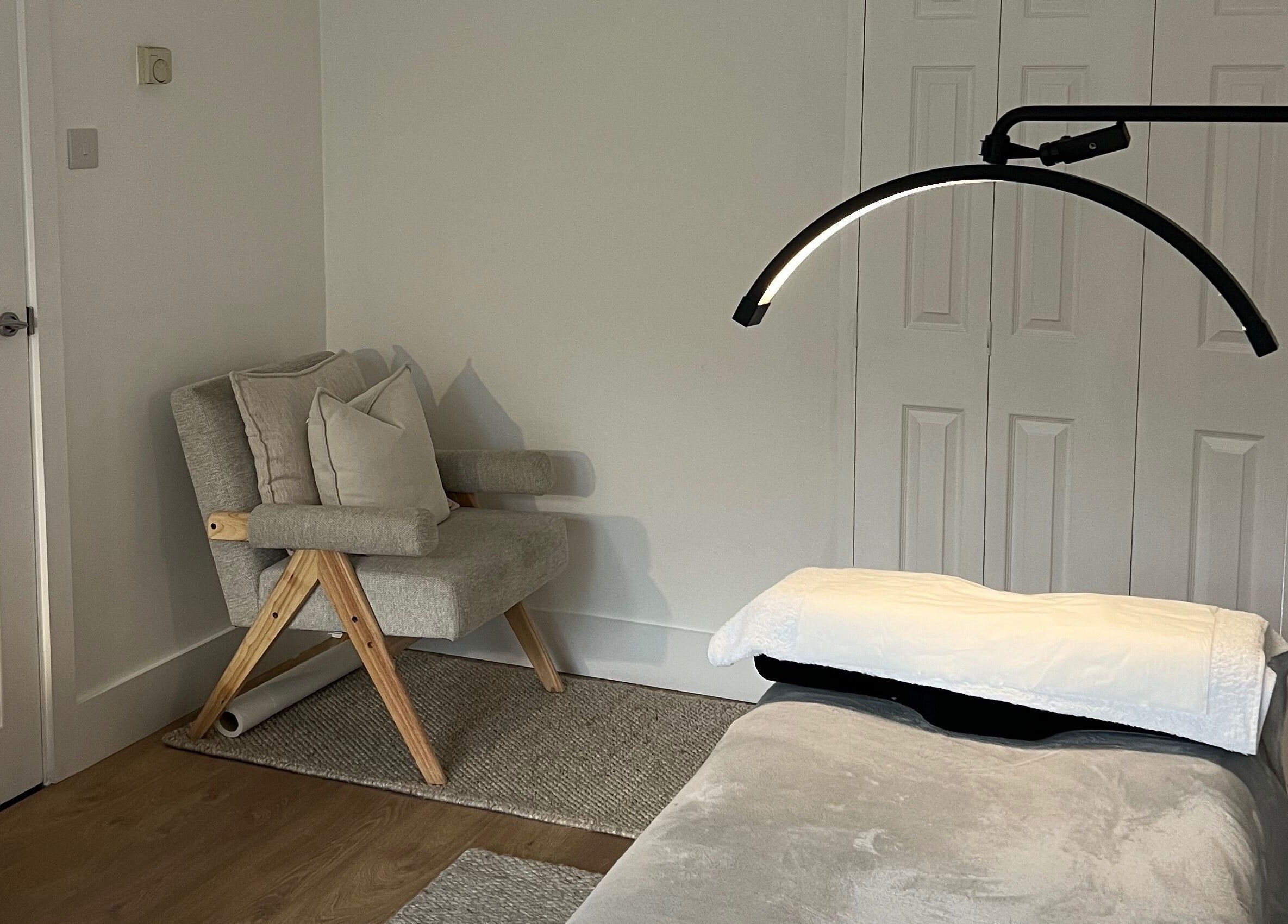 Calm treatment room at Beauté by Michèle, North Warnborough, England, GB featuring a cozy chair and massage table.
