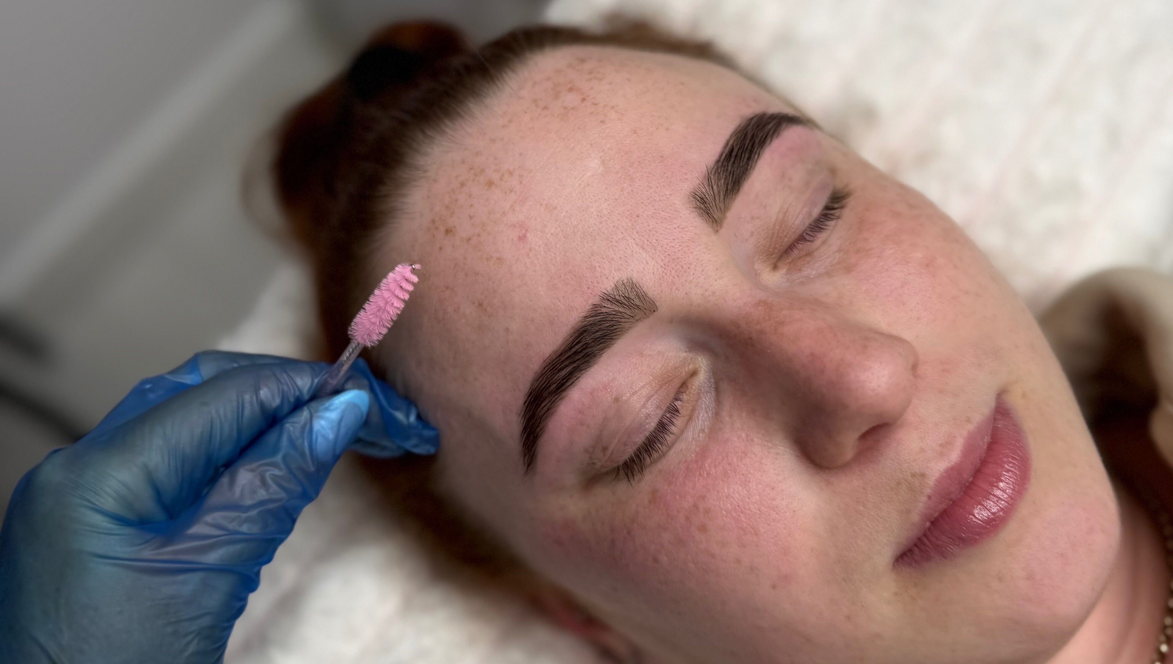 Enhance brows at Lash Tee in Desborough, England with precise treatment using pink brush tool.