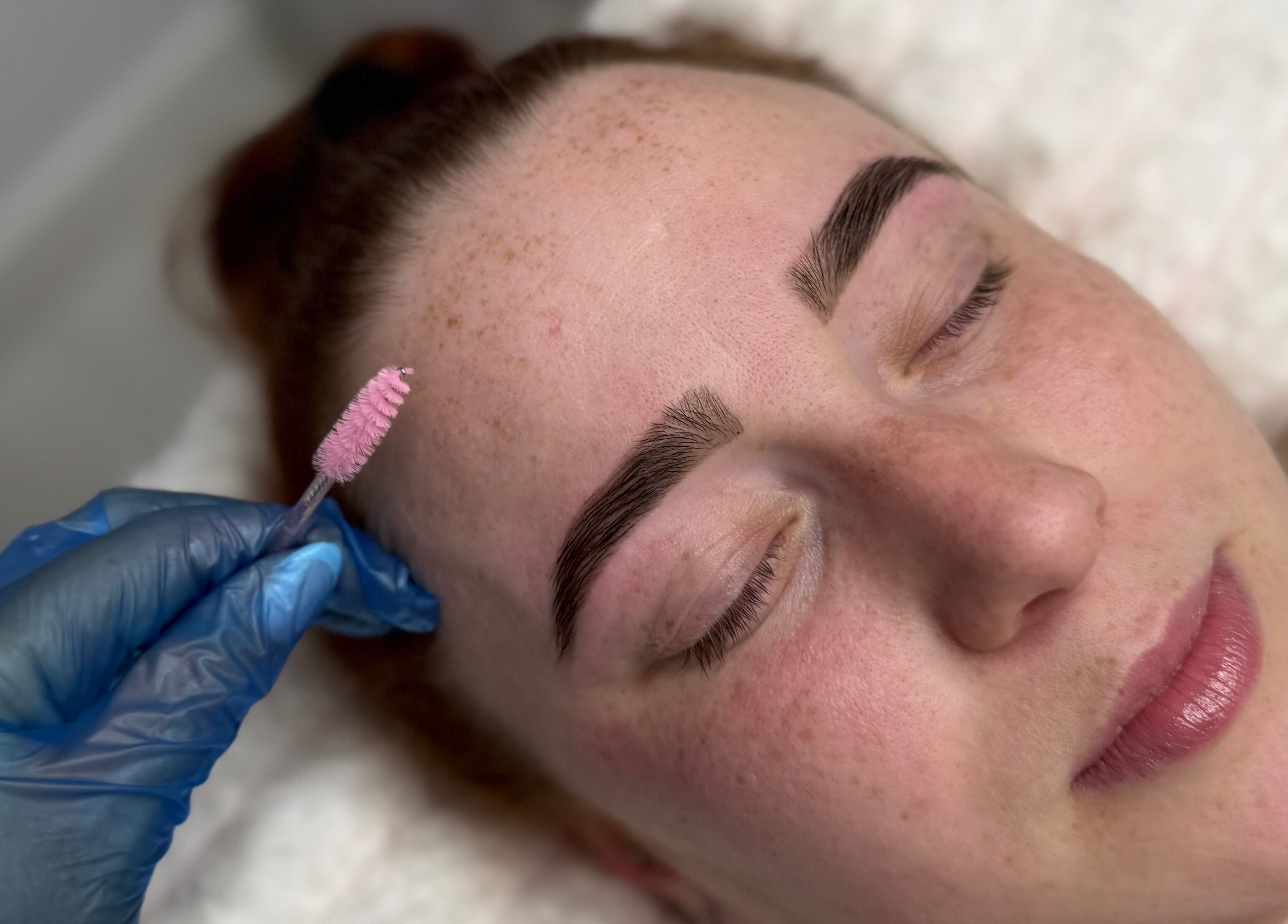 Enhance brows at Lash Tee in Desborough, England with precise treatment using pink brush tool.