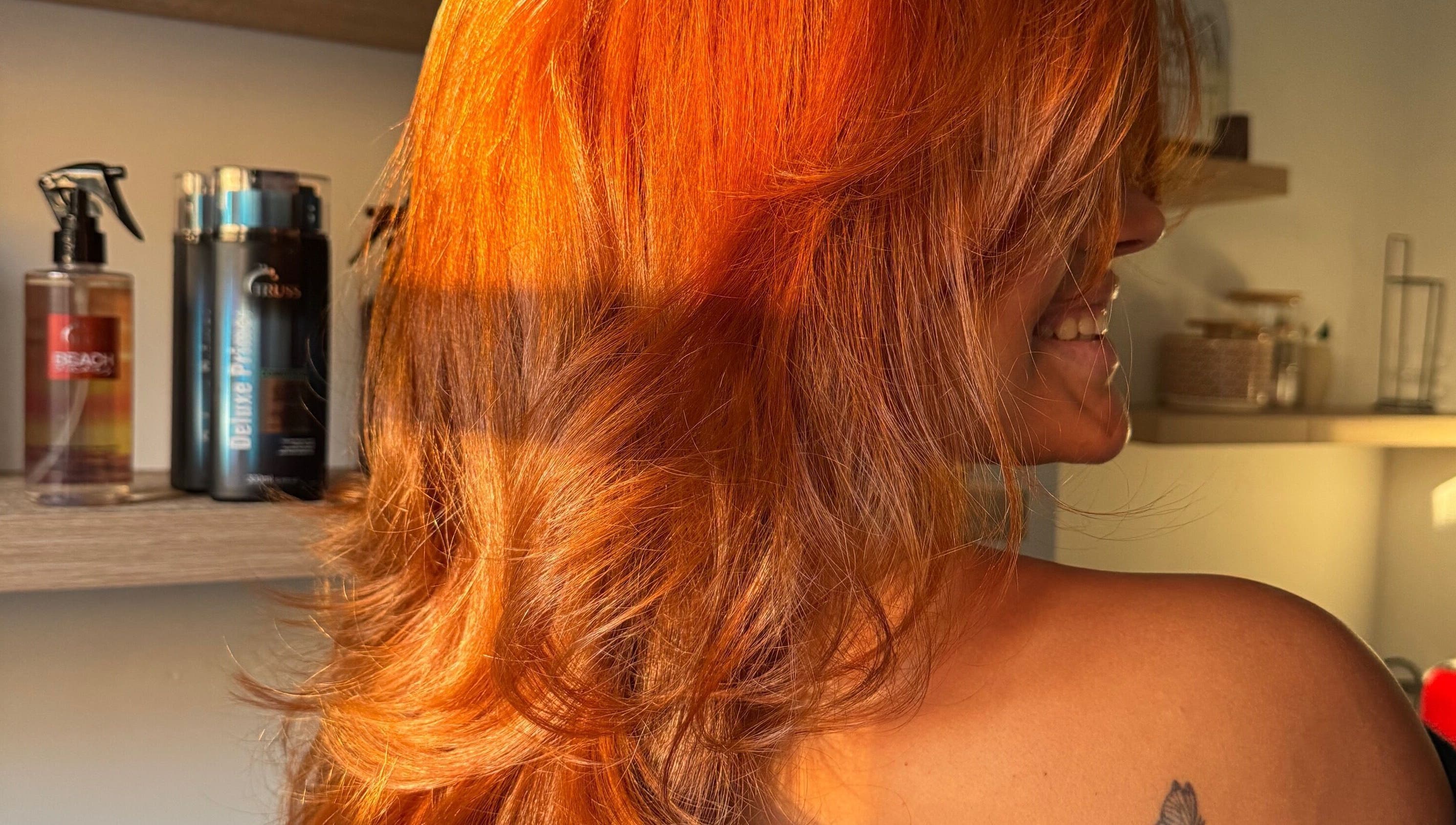 Schitterende rode haarstijl bij Dary in Kortrijk, Vlaams Gewest, BE, met producten op de achtergrond.