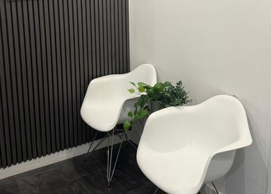 Modern white chairs and plants in a sleek waiting area at Enhanced Aesthetics Scotland, Glasgow, Scotland, GB.