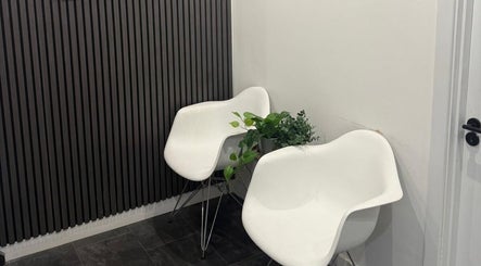 Modern white chairs and plants in a sleek waiting area at Enhanced Aesthetics Scotland, Glasgow, Scotland, GB.