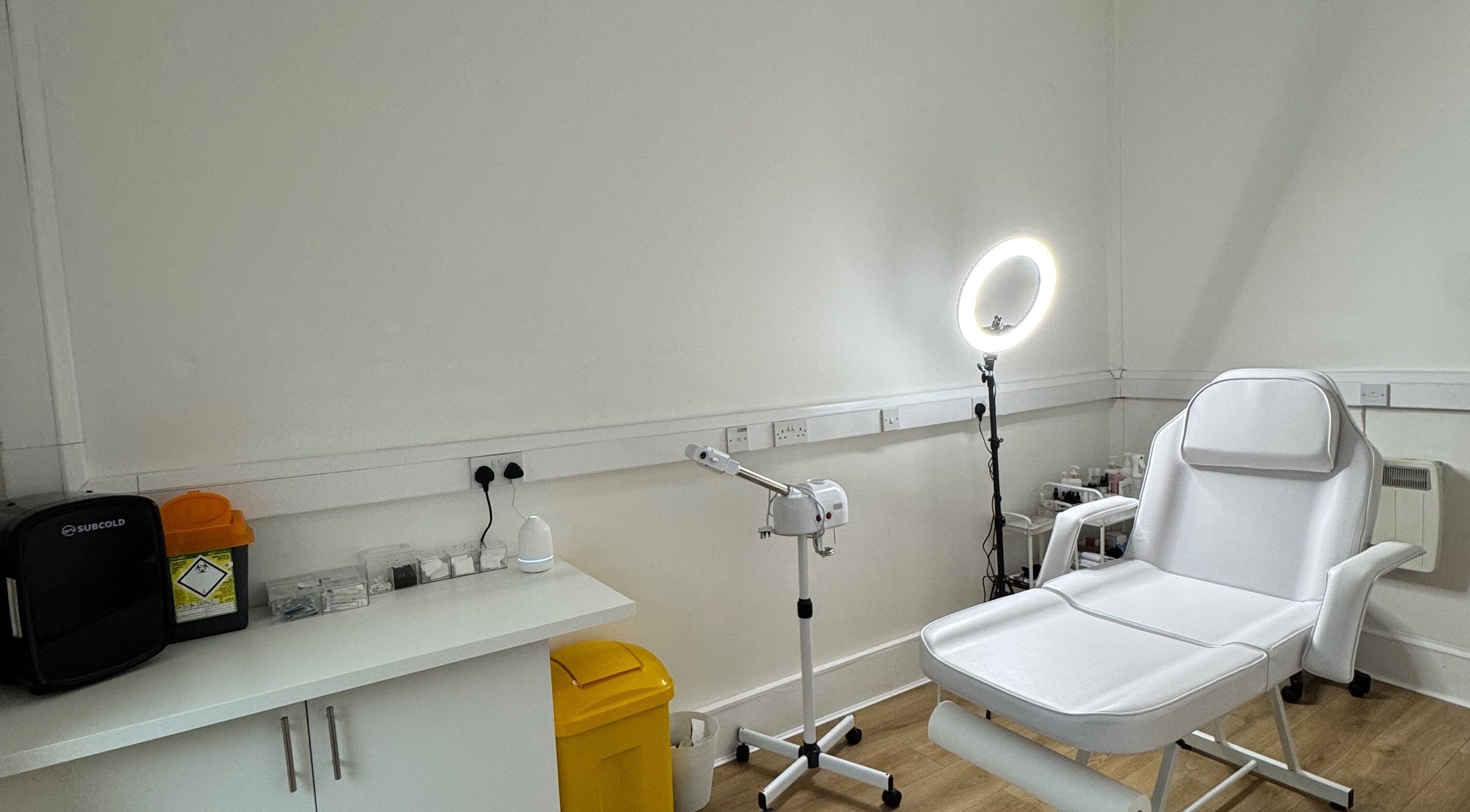 Modern treatment room at The Skin Collective, Glasgow, Scotland, GB, featuring a white chair and beauty equipment.