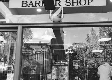 Exterior of Broadway Barbershop in Ultimo, NSW, AU, with stylish signage and iconic barber poles.