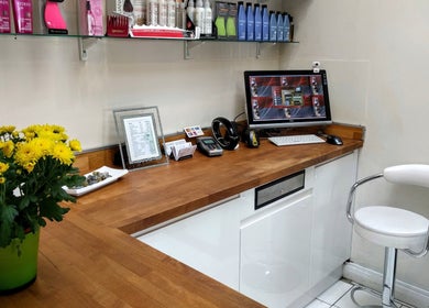Reception desk at Hair Workshop, Maidstone, England, GB, with wooden counter and flowers.