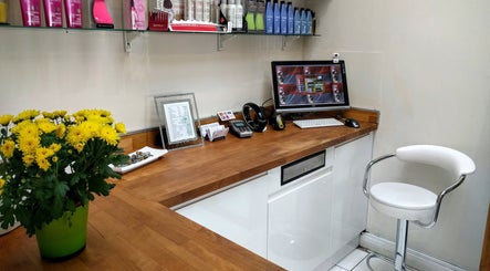 Reception desk at Hair Workshop, Maidstone, England, GB, with wooden counter and flowers.