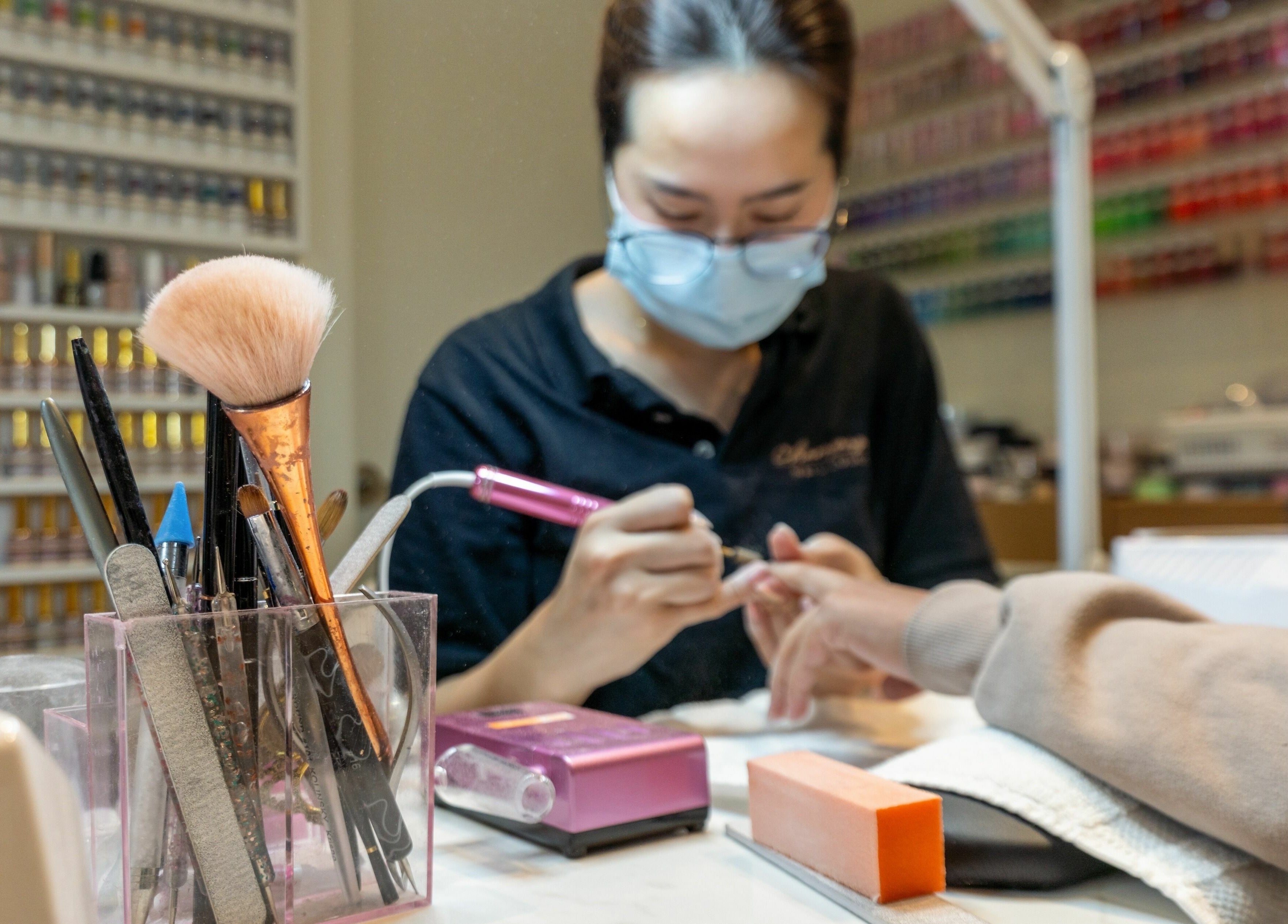 Nail technician at Champagne Nail Lounge in New Westminster crafting elegance with precision tools.