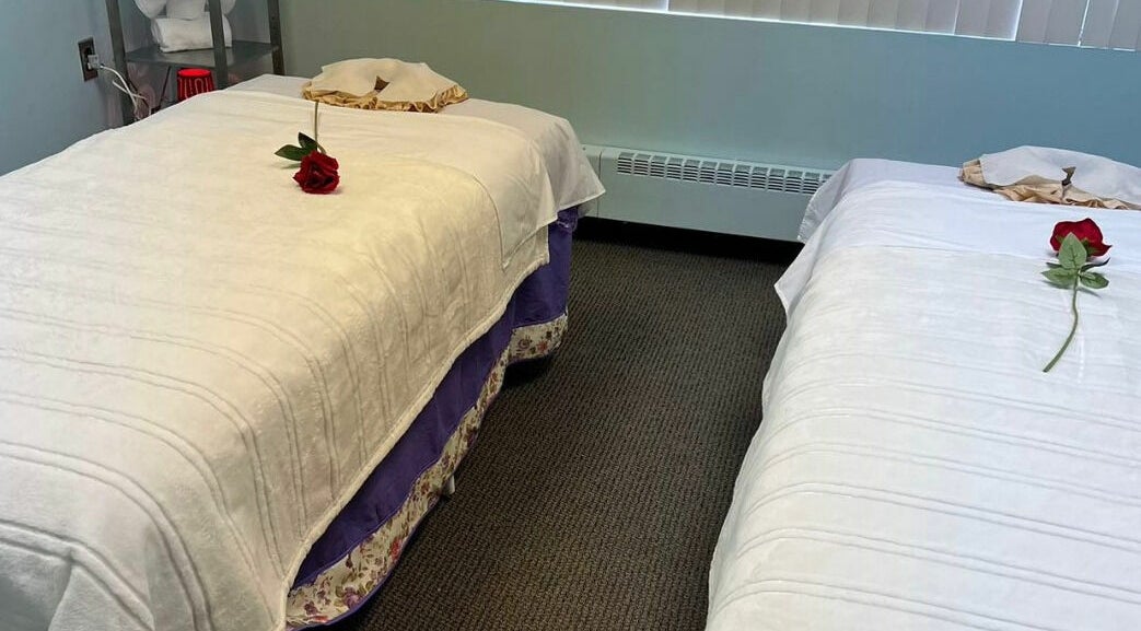Peaceful massage room at RTC Massage, Reston, Virginia, US with two beds adorned with red roses.