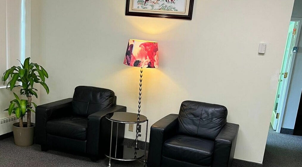Comfortable seating area at RTC Massage in Reston, Virginia, US with leather chairs and a floral lamp.