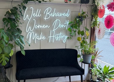 Keelys vibrant lounge decor with neon sign 'Well Behaved Women Don't Make History' in Faringdon, England, GB.