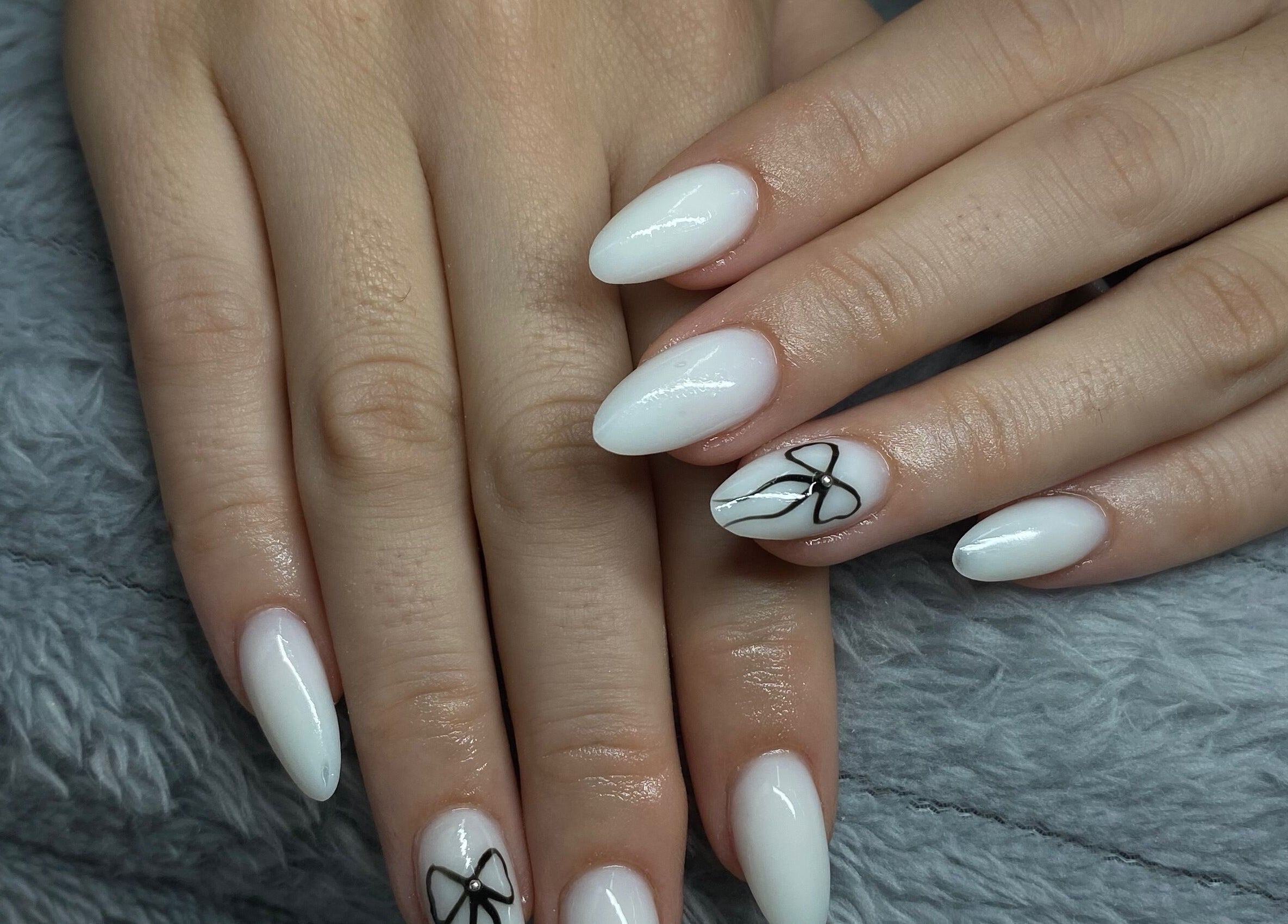 Elegant white nails with black bow design at Azalea Beauty Spa, Tzaneen, Limpopo, ZA.
