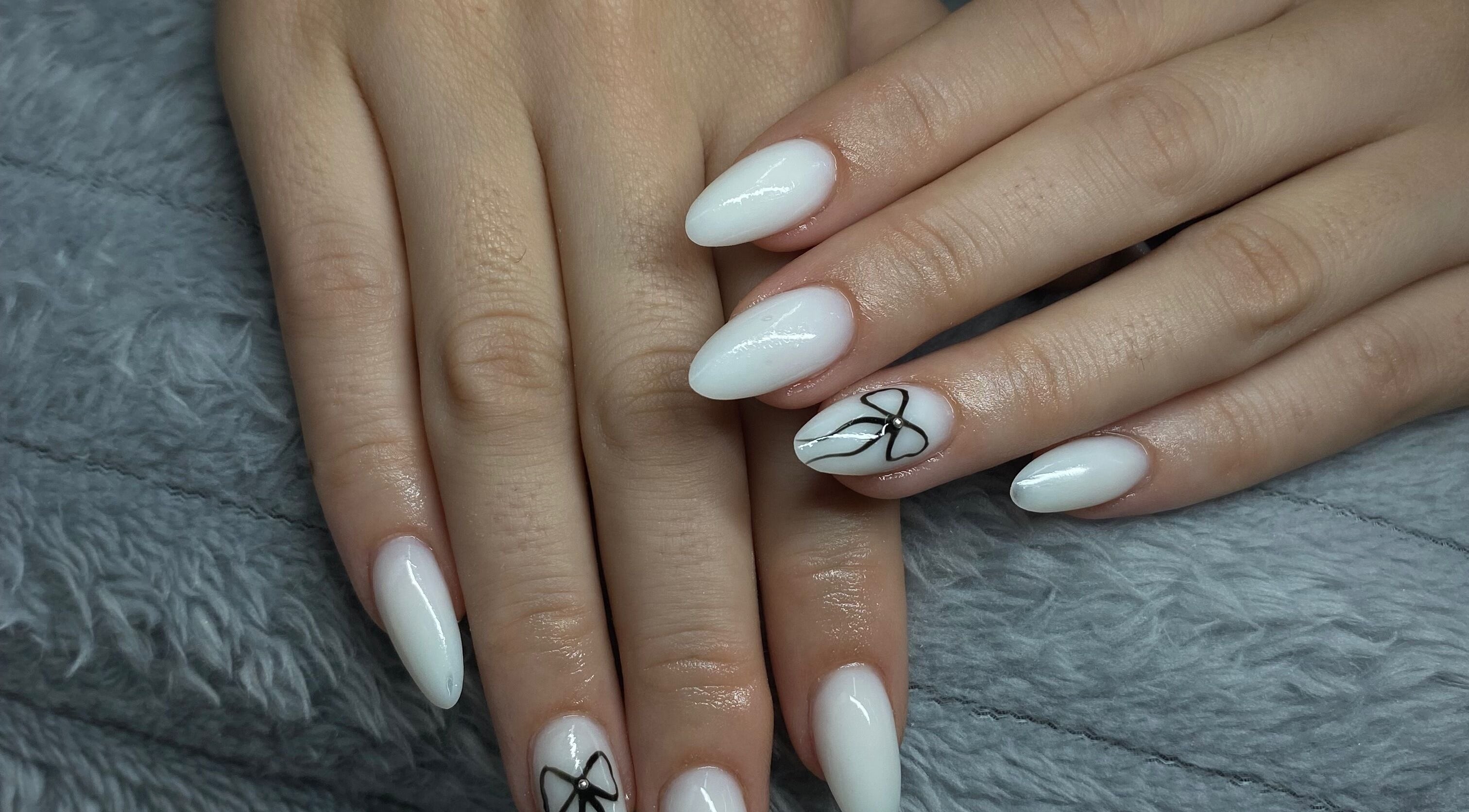 Elegant white nails with black bow design at Azalea Beauty Spa, Tzaneen, Limpopo, ZA.