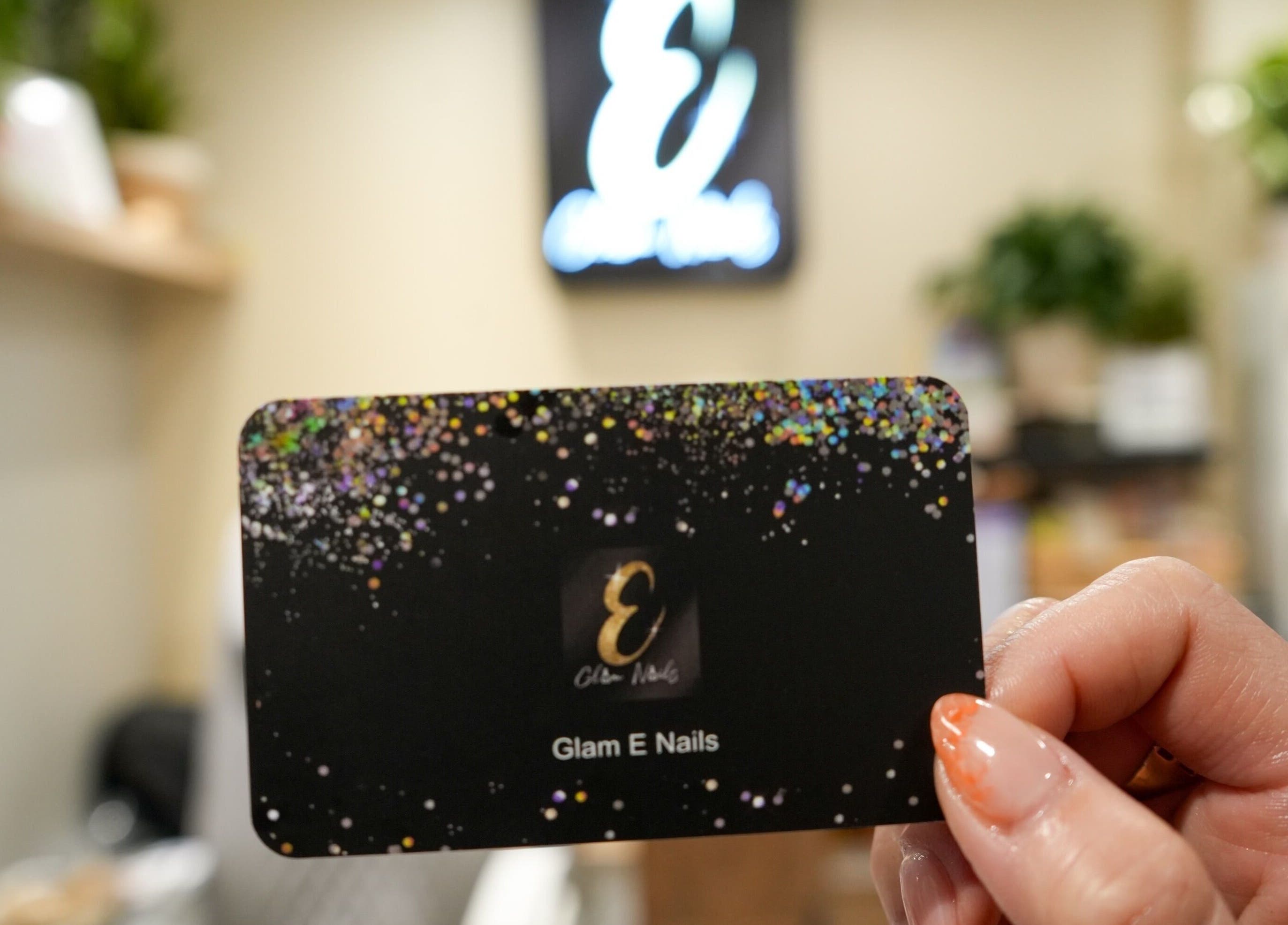 Hand holding a Glam E Nails gift card with glitter design in Arlington, Virginia, US.