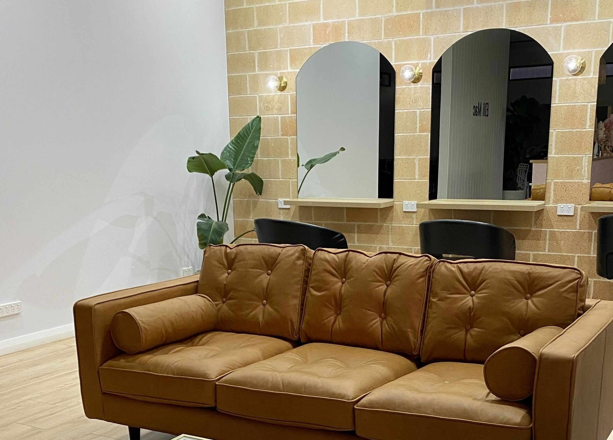 Elli Mac Salon's stylish seating area in Waroona, Western Australia, AU with brown sofa and mirrors.