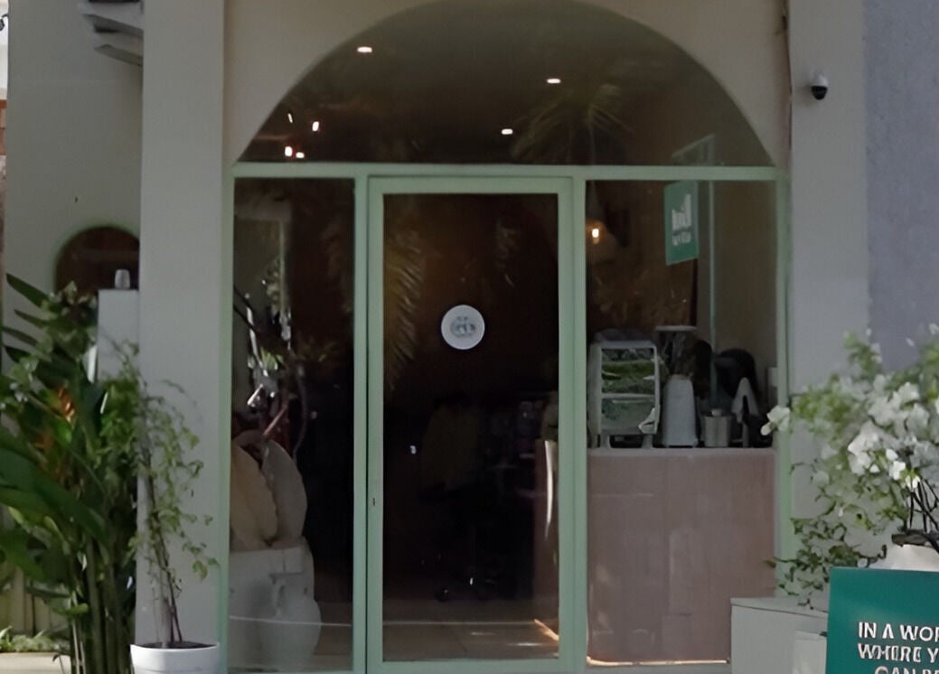 Entrance of Kind - Nails & Spa in Bali, Bali, ID, featuring lush plants and inviting glass doors.