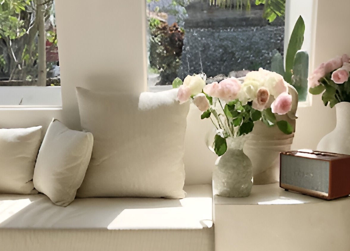 Cozy lounge with white cushions and flowers at Kind - Nails & Spa, Bali, ID. Relaxing ambiance and natural light.