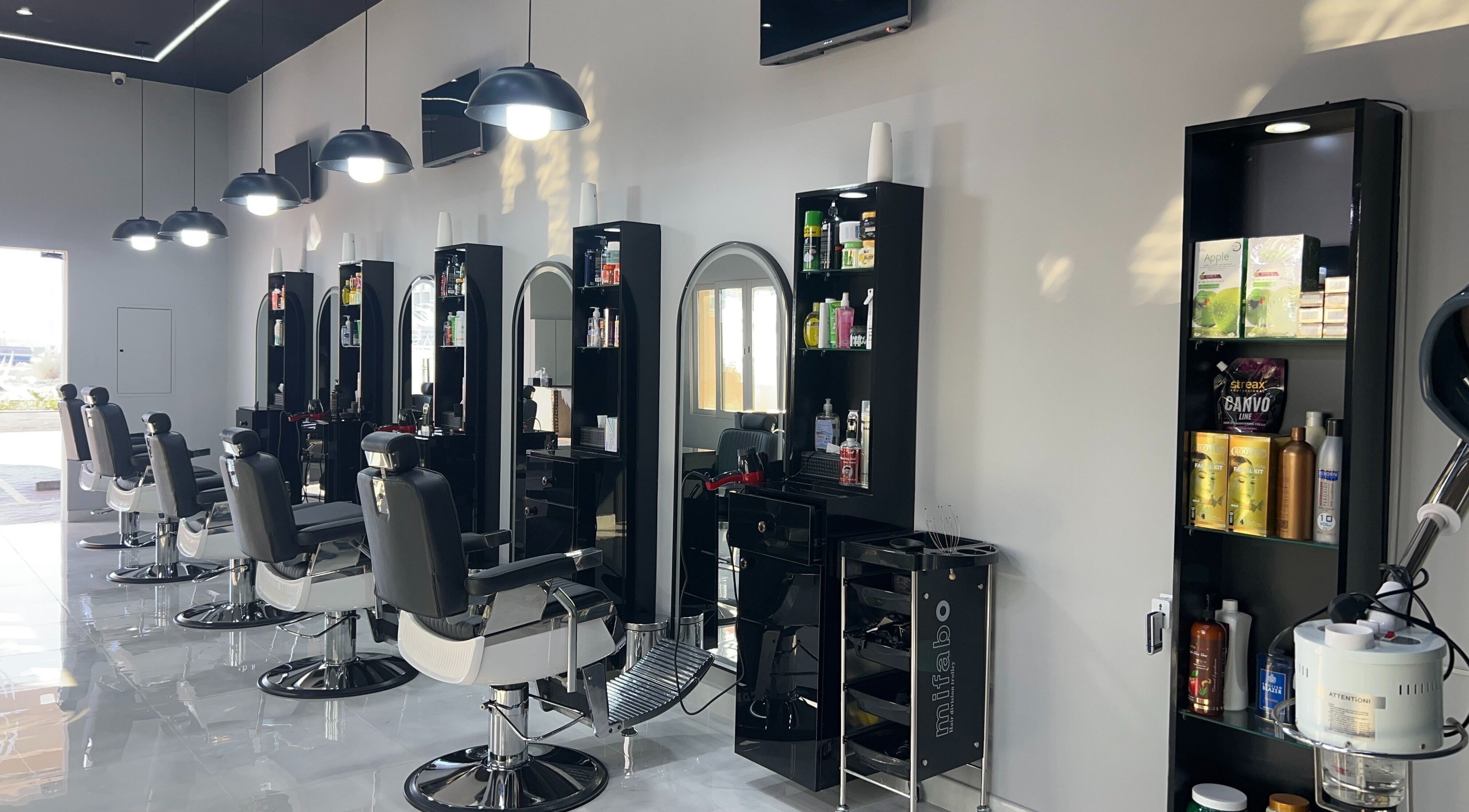 Chic interior at Barb Bros, Dubai, featuring modern barber chairs and styling stations with products.