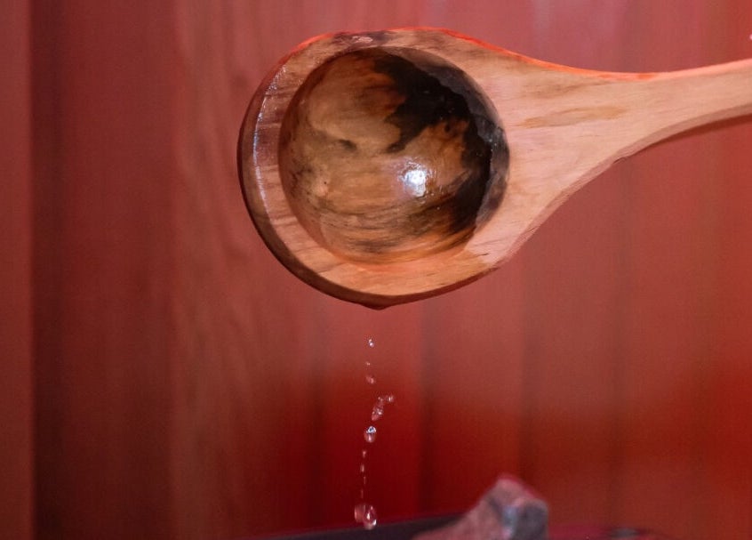Wooden ladle pouring water in sauna at Rewind, Currumbin Waters, Queensland, AU offering serene wellness experiences.