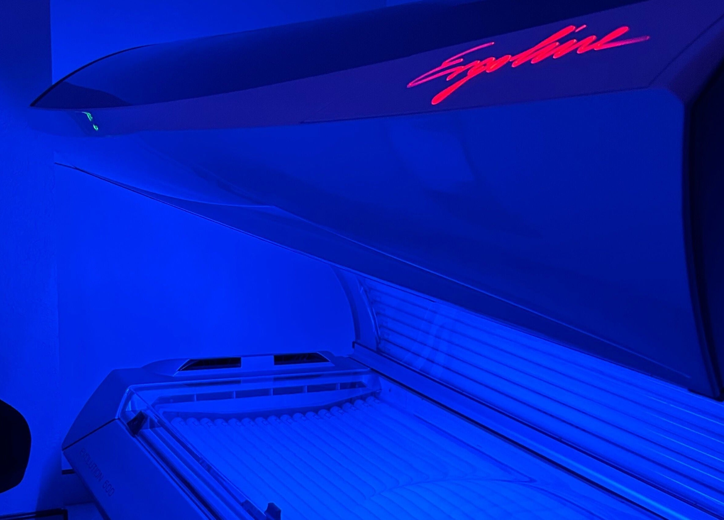 Modern tanning bed glowing blue at Glow Salon, Salford, England, GB, ensuring a premium tanning experience.