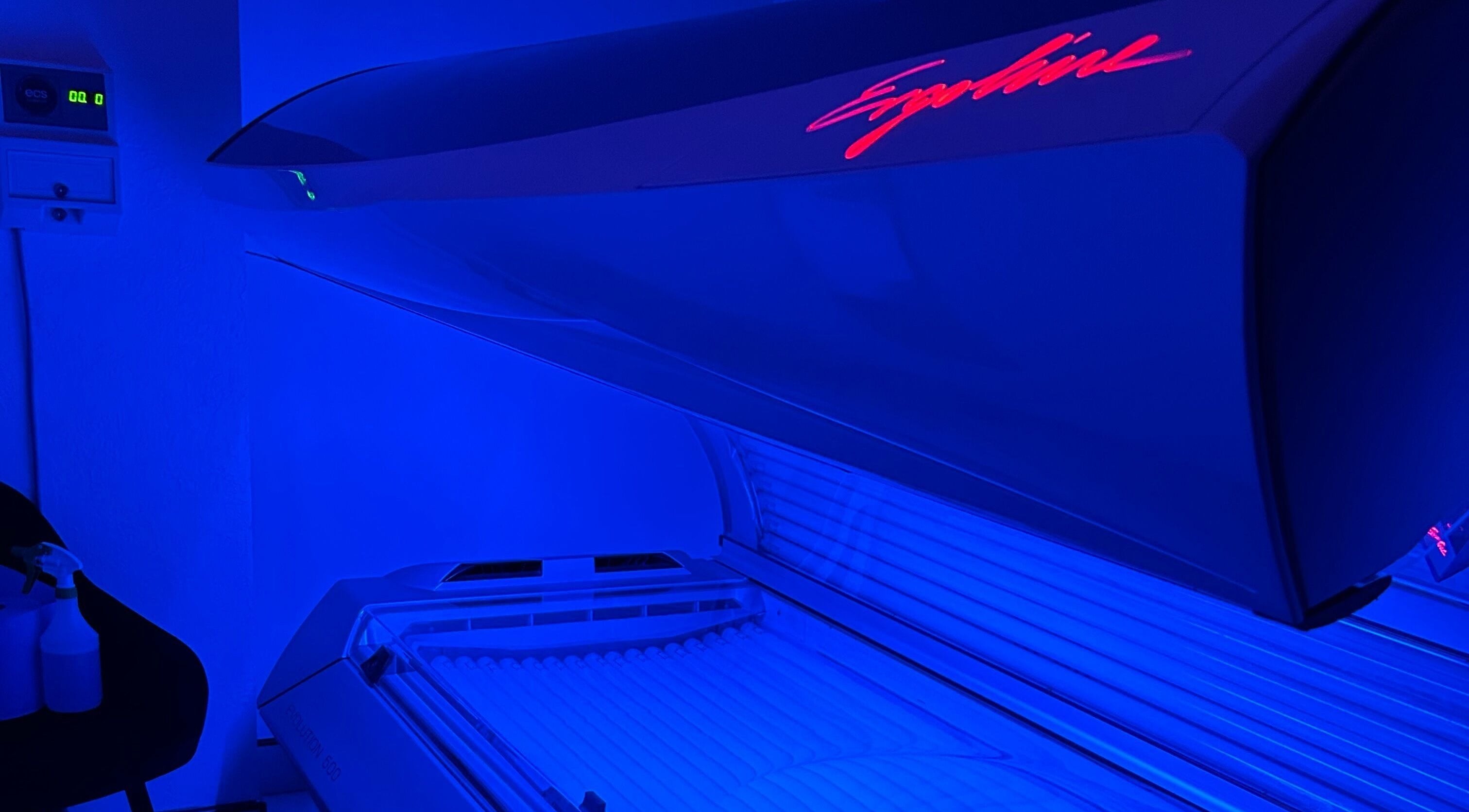 Modern tanning bed glowing blue at Glow Salon, Salford, England, GB, ensuring a premium tanning experience.