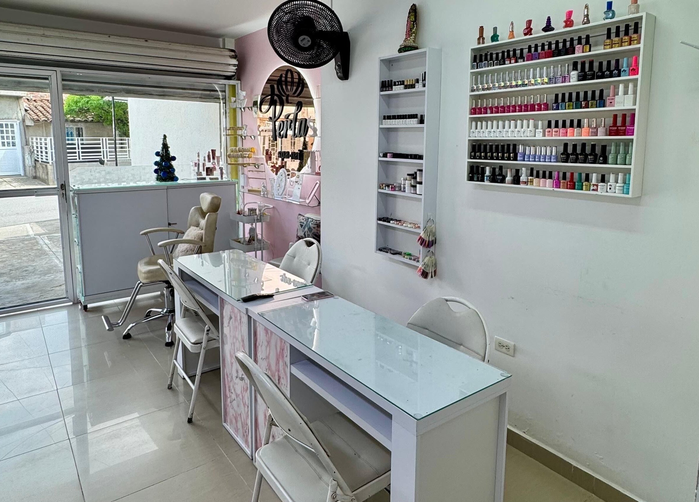 Interior de Perla spa nails en Tuluá, Valle Del Cauca, CO con sillas y esmaltes coloridos.