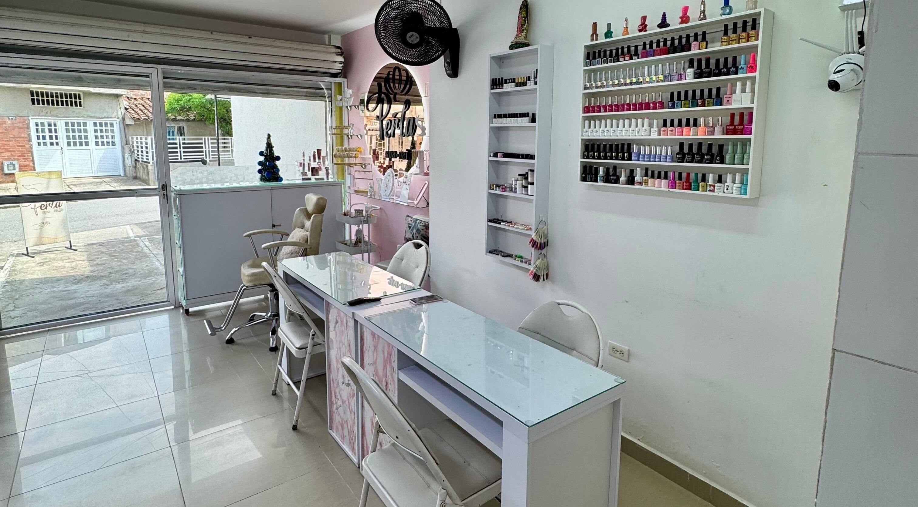 Interior de Perla spa nails en Tuluá, Valle Del Cauca, CO con sillas y esmaltes coloridos.