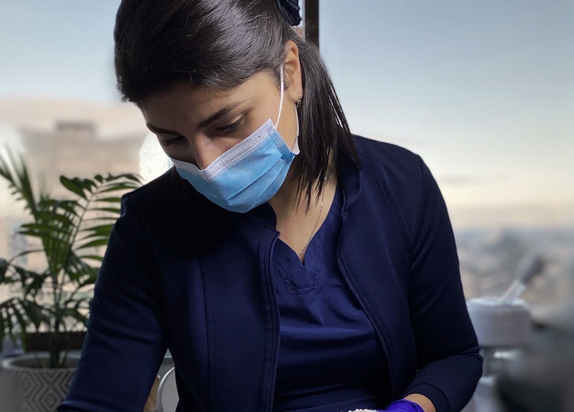 Esteticista en De Florencia, Temuco, Araucanía, CL, realiza tratamiento facial con mascarilla de seguridad.